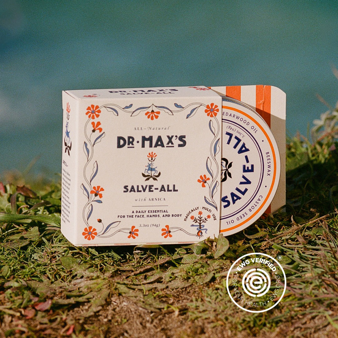 Dr. Max's Salve-All packaging on grass with a blurred natural background