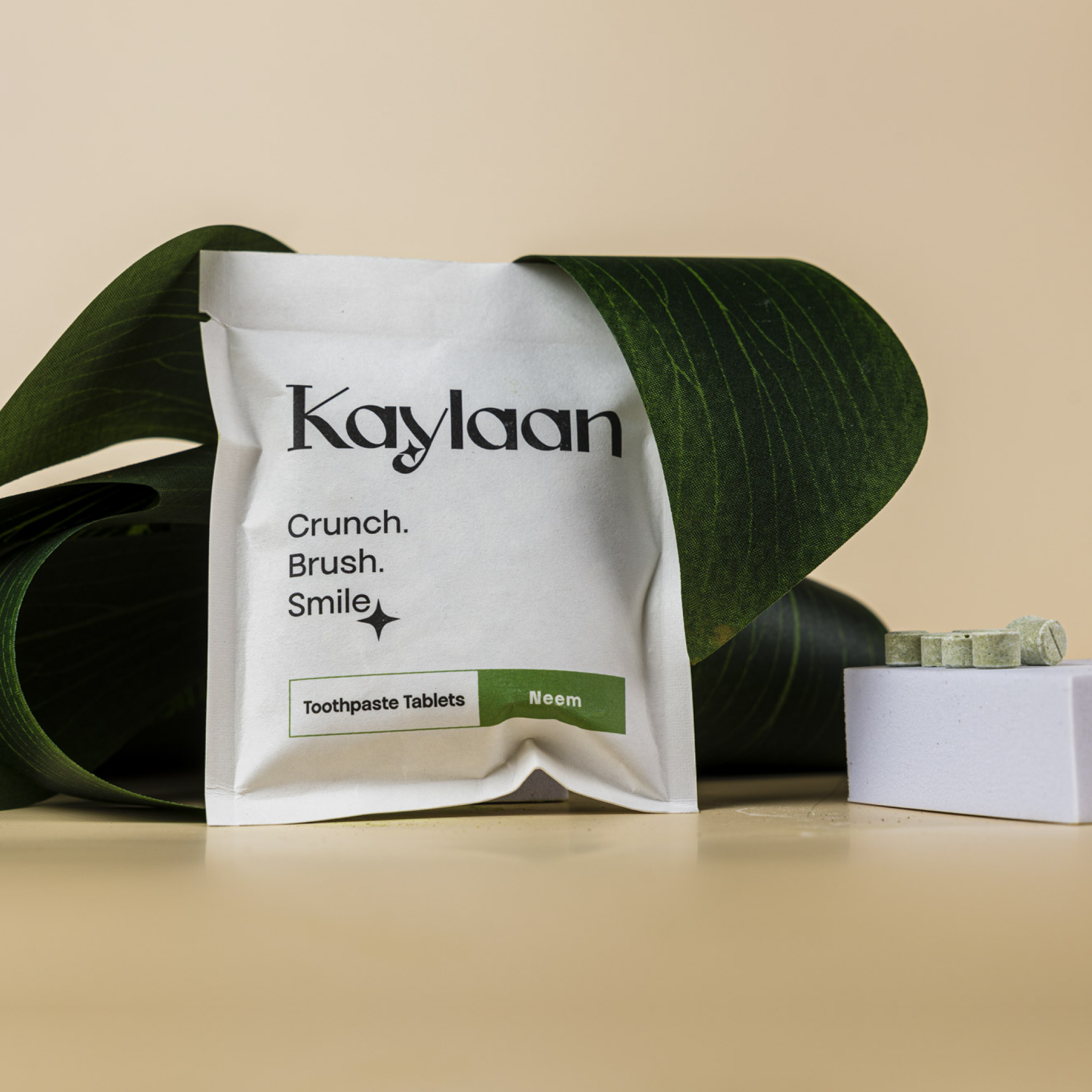 Kaylaan toothpaste tablets packaging with green leaves on a beige background